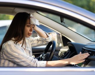 Exhausted young woman suffering from heat inside car